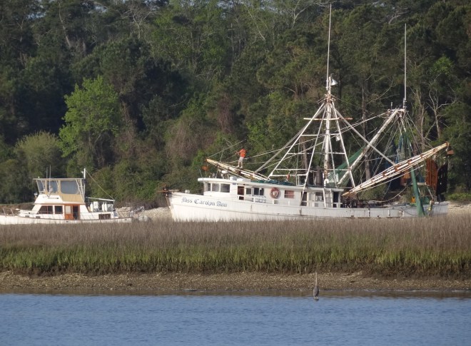 A trawler squeezes past a shrimper preparing to head out the inlet.