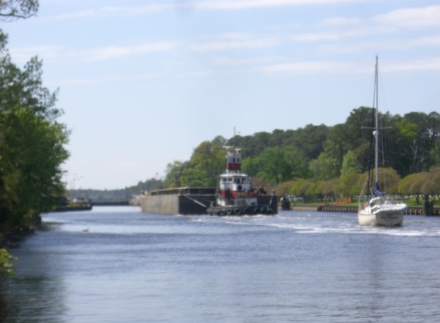 Tug and barge enter lock followed by sailboat