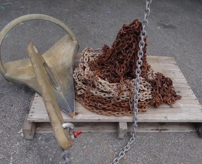 Anchor with new chain attached, sits next to the rust pile