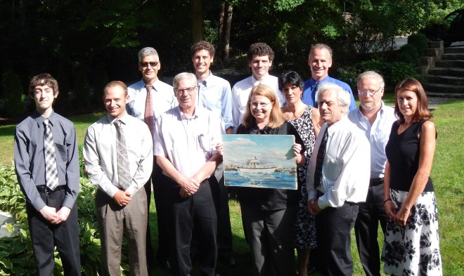 Group photo in the garden featuring a painting of m/v Spray